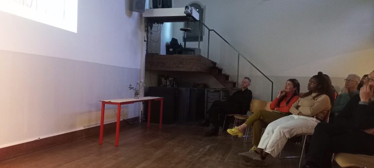 Guests seated along a wall listening during the Beyond Geography seminar