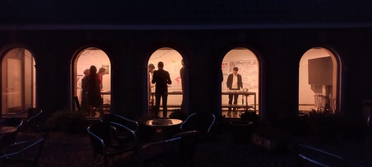 Silhouettes of people in a row of lit arched windows at night