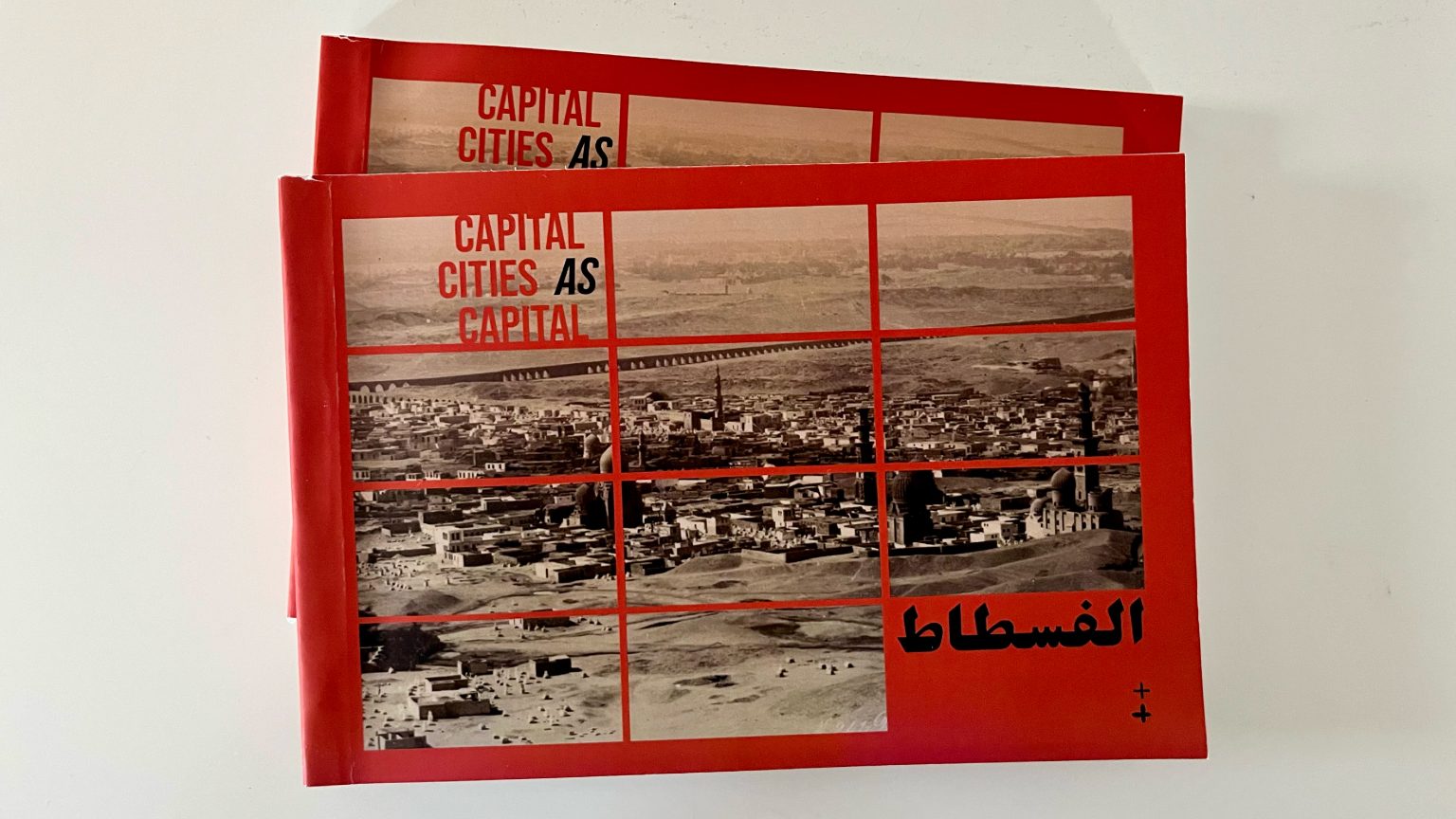 Copies of the book al-Fustat: Capital Cities as Capital, with red covers showing an aerial photograph