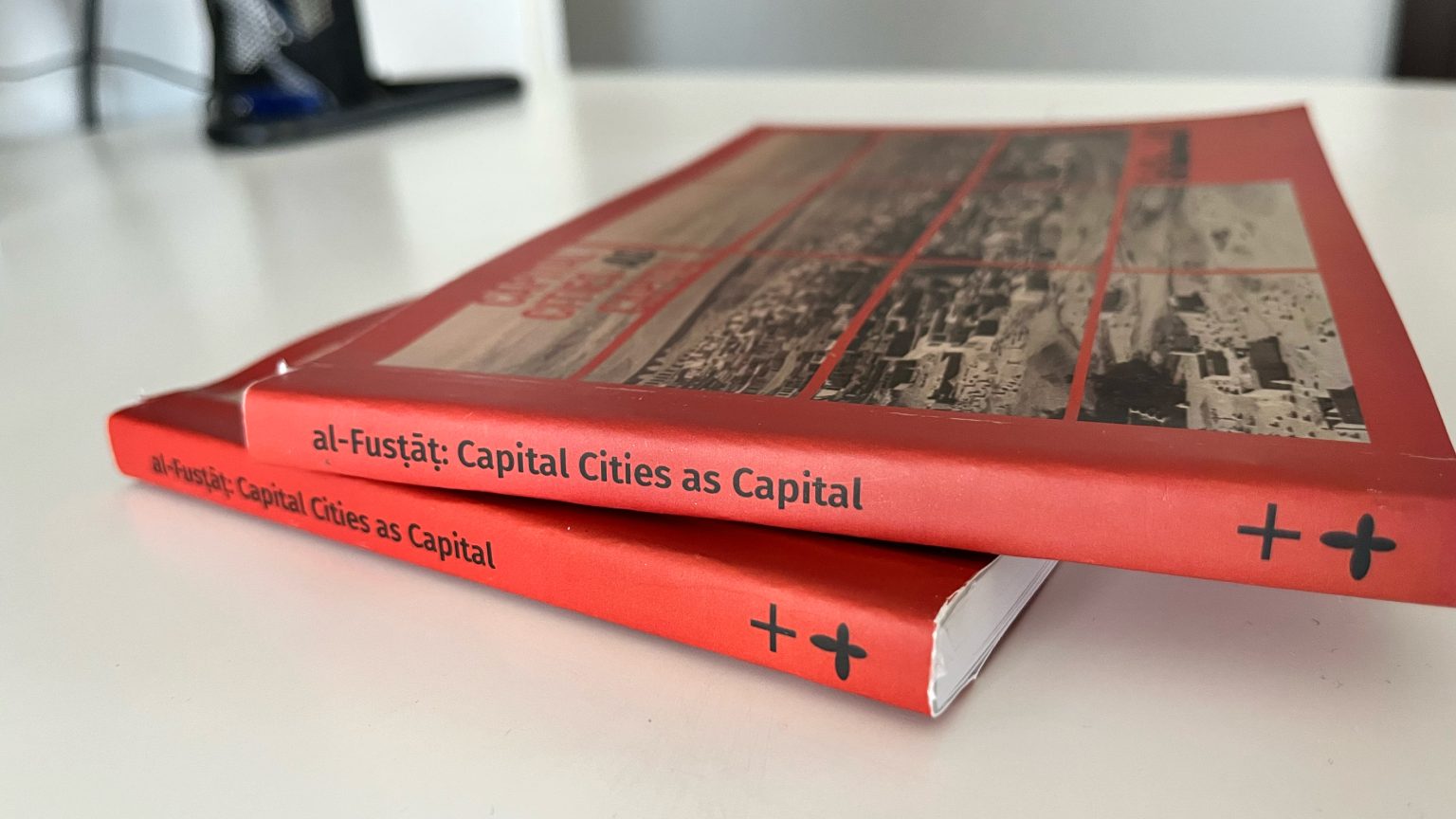 Two copies of the red book al-Fustat: Capital Cities as Capital lying on a table