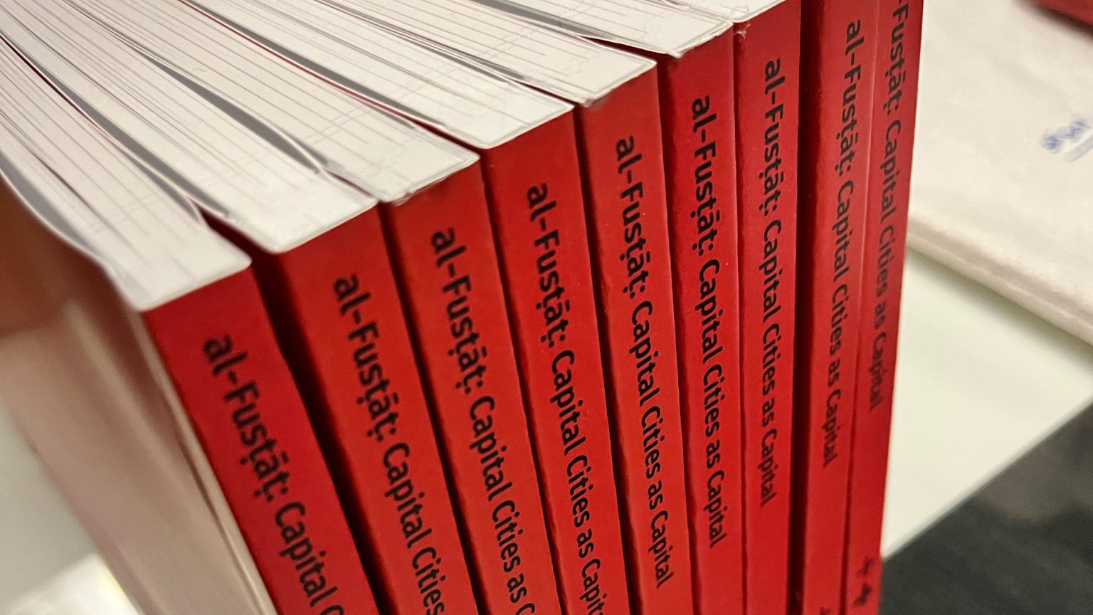 Spines of a row of red books titled al-Fustat: Capital Cities as Capital