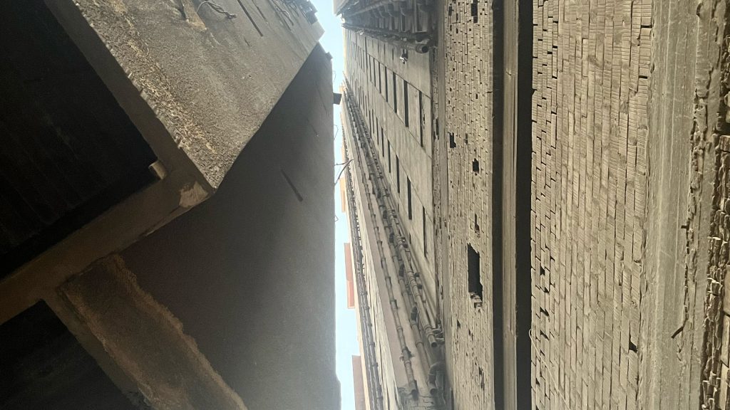 Looking up between two weathered building facades in Cairo, from the Kairo Lesen project