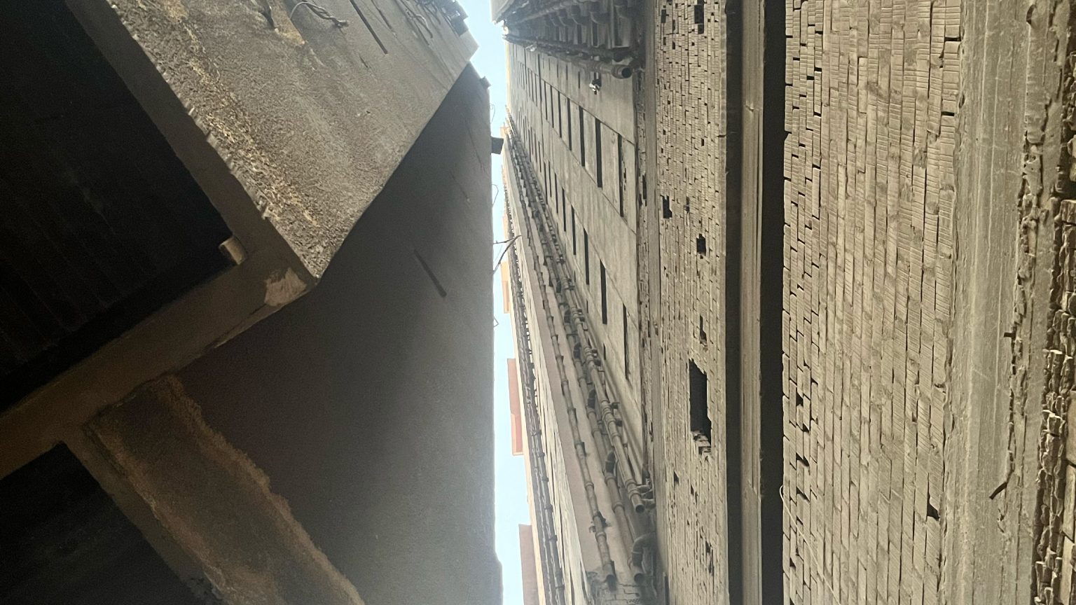 Looking up between two weathered building facades in Cairo, from the Kairo Lesen project