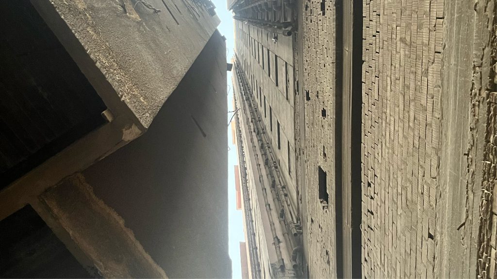 Looking up between two weathered building facades in Cairo, from the Kairo Lesen project