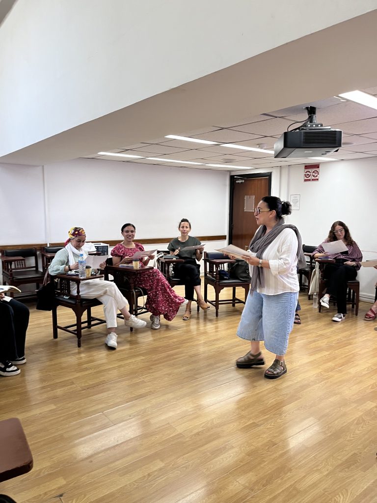 A facilitator speaks to participants seated in a circle during the Experimenting with Urbanity workshop