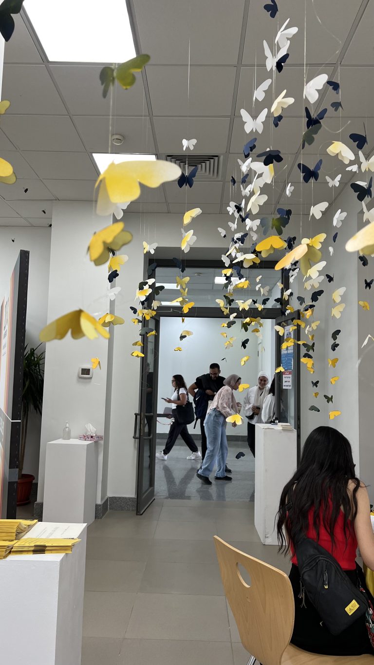 Black, white and yellow paper butterflies hanging from the ceiling of the Among Us exhibition corridor