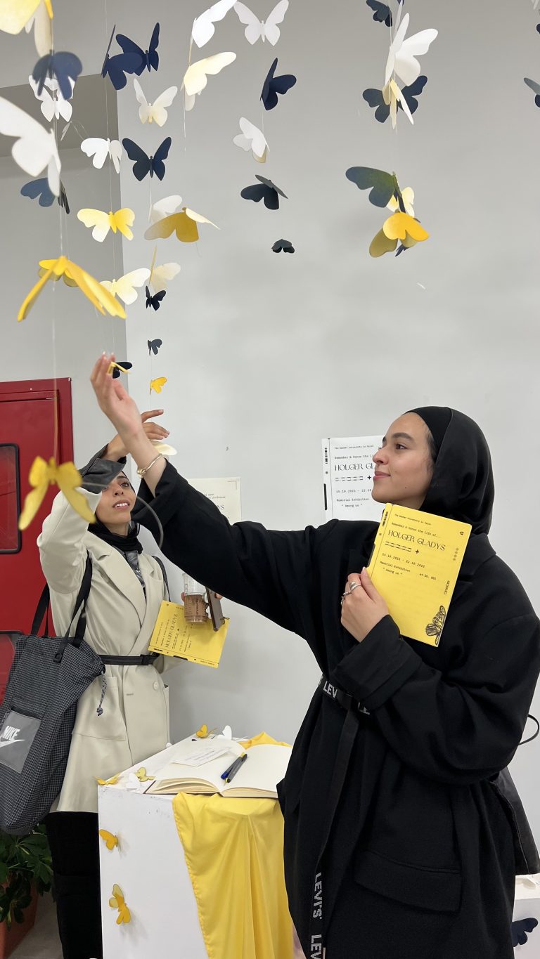 A visitor hangs a yellow paper butterfly among the suspended butterflies at the Among Us exhibition