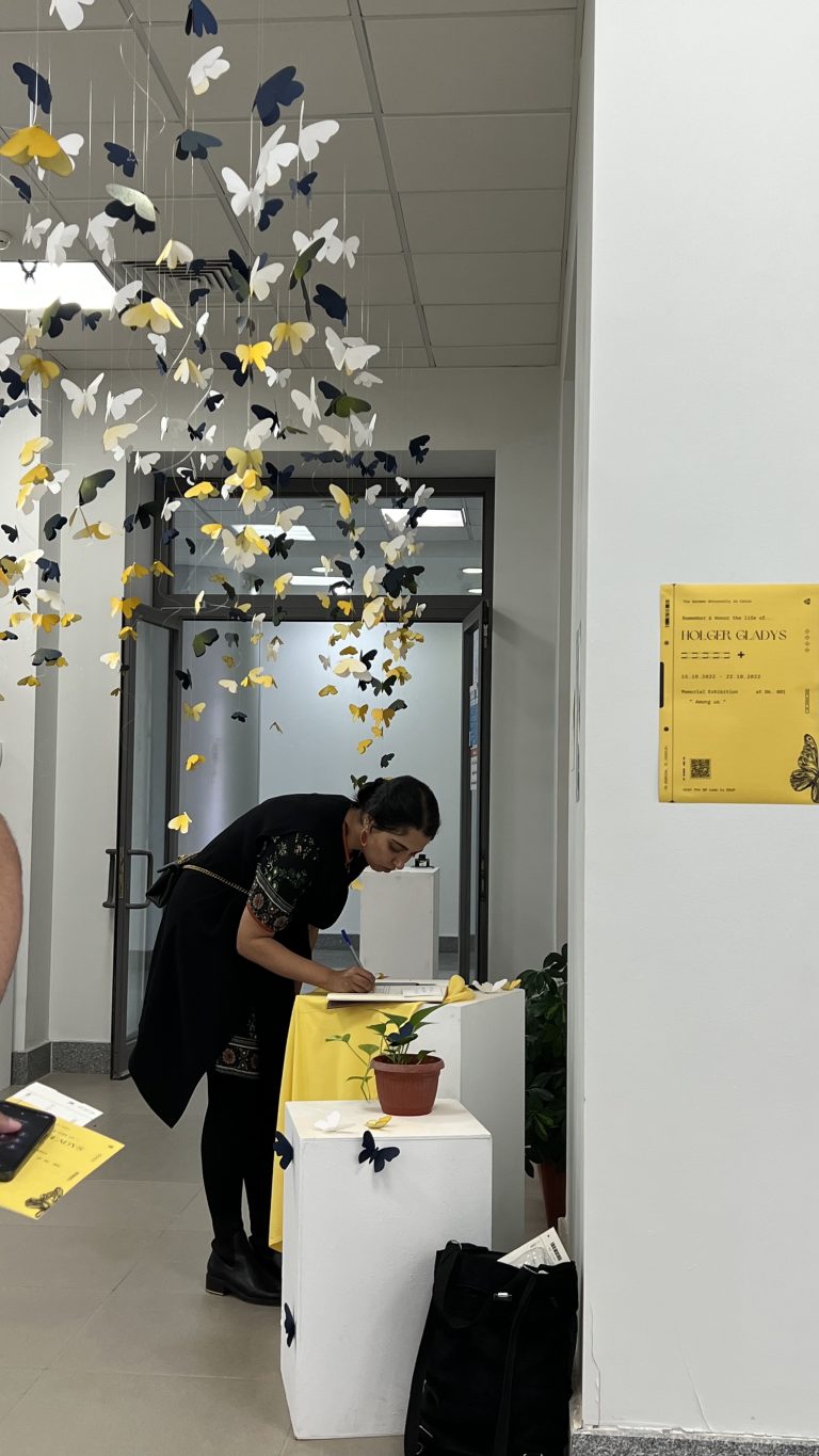 A visitor writes at a table beneath the hanging paper butterflies at the Among Us exhibition